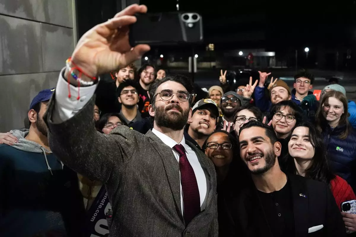 Streamer Hasan Piker, left, and Abdul El-Sayed, a progressive candidate in the Democratic primary for U.S. Senate in Michigan, center right, take a selfie with young fans following a campaign event, Tuesday, April 7, 2026, at the University of Michigan in Ann Arbor, Mich. (AP Photo/Julia Demaree Nikhinson)