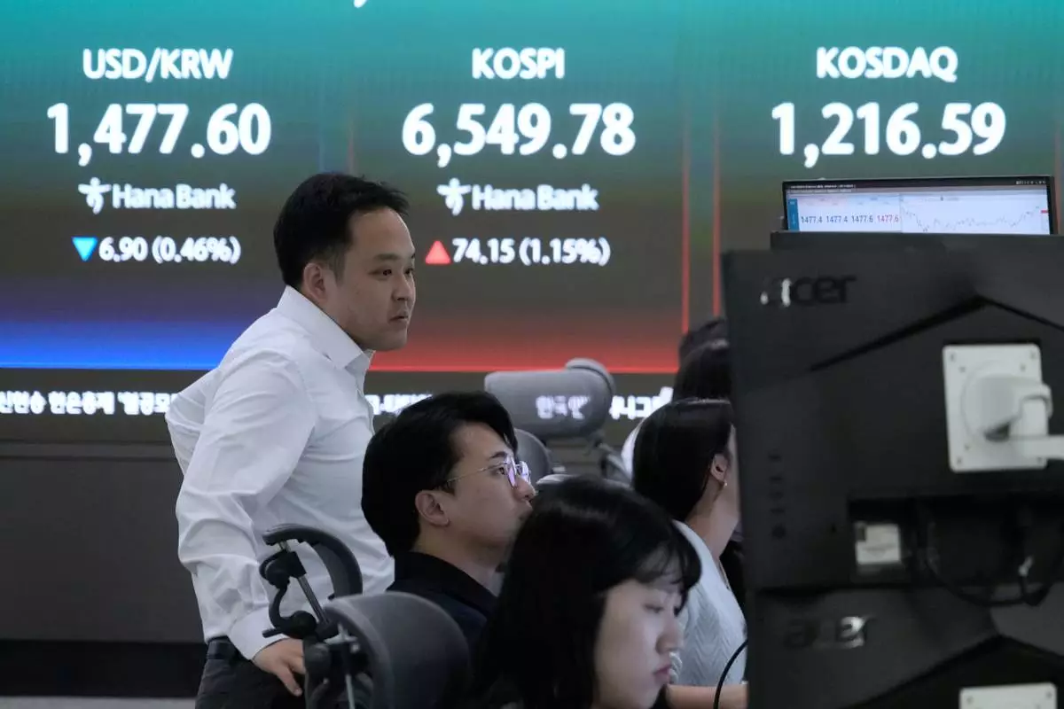 Currency traders watch monitors near a screen showing the Korea Composite Stock Price Index (KOSPI), rear center, and the foreign exchange rate between U.S. dollar and South Korean won, rear left, at the foreign exchange dealing room of the Hana Bank headquarters in Seoul, South Korea, Monday, April 27, 2026. (AP Photo/Ahn Young-joon)