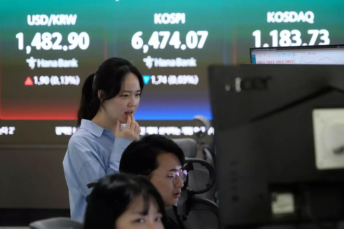 A currency trader watches monitors near a screen showing the Korea Composite Stock Price Index (KOSPI), top center, and the foreign exchange rate between U.S. dollar and South Korean won, top center left, at the foreign exchange dealing room of the Hana Bank headquarters in Seoul, South Korea, Friday, April 24, 2026. (AP Photo/Ahn Young-joon)