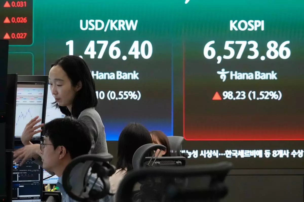 Currency traders work near a screen showing the Korea Composite Stock Price Index (KOSPI), right, and the foreign exchange rate between U.S. dollar and South Korean won at the foreign exchange dealing room of the Hana Bank headquarters in Seoul, South Korea, Monday, April 27, 2026. (AP Photo/Ahn Young-joon)