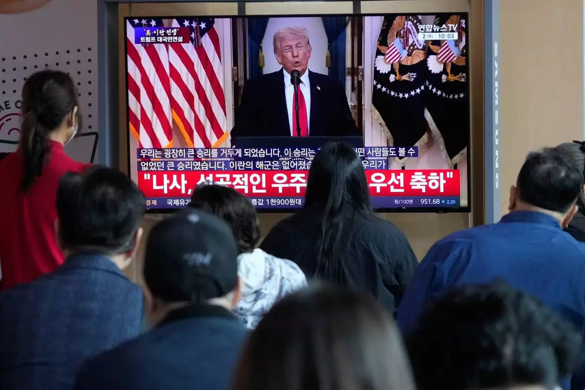 People watch a TV screen showing a live broadcast of U.S. President Donald Trump's speech at the Seoul Railway Station in Seoul, South Korea, Thursday, April 2, 2026. (AP Photo/Ahn Young-joon)