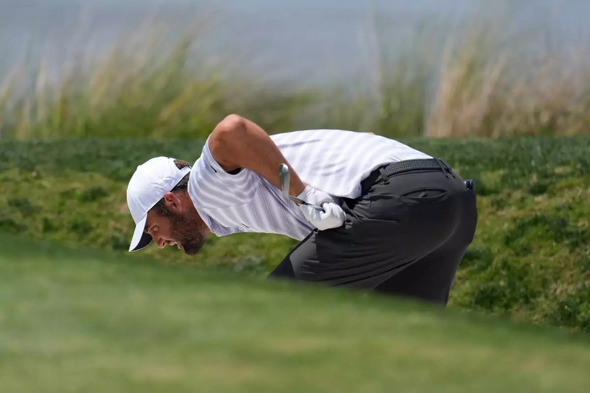 Scottie Scheffler inspects his ball in a bunker on the 18th hole during the second round at the RBC Heritage golf tournament Friday, April 17, 2026, in Hilton Head, S.C. (AP Photo/Mike Stewart)