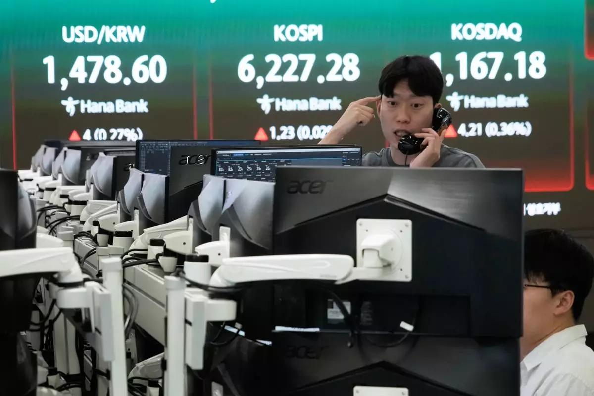 A currency trader talks on the phone near a screen showing the Korea Composite Stock Price Index (KOSPI), top center, and the foreign exchange rate between U.S. dollar and South Korean won, top center left, at the foreign exchange dealing room of the Hana Bank headquarters, in Seoul, South Korea, Friday, April 17, 2026. (AP Photo/Ahn Young-joon)