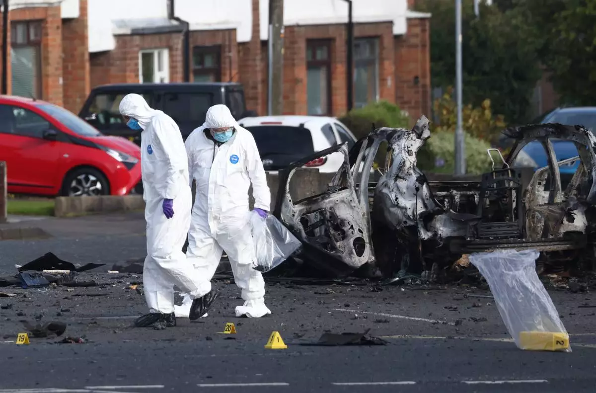 Forensic investigators inspect the site of a car bomb that exploded outside Dunmurry police station in South Belfast, Sunday, April 26, 2026. (AP Photo/Peter Morrison)