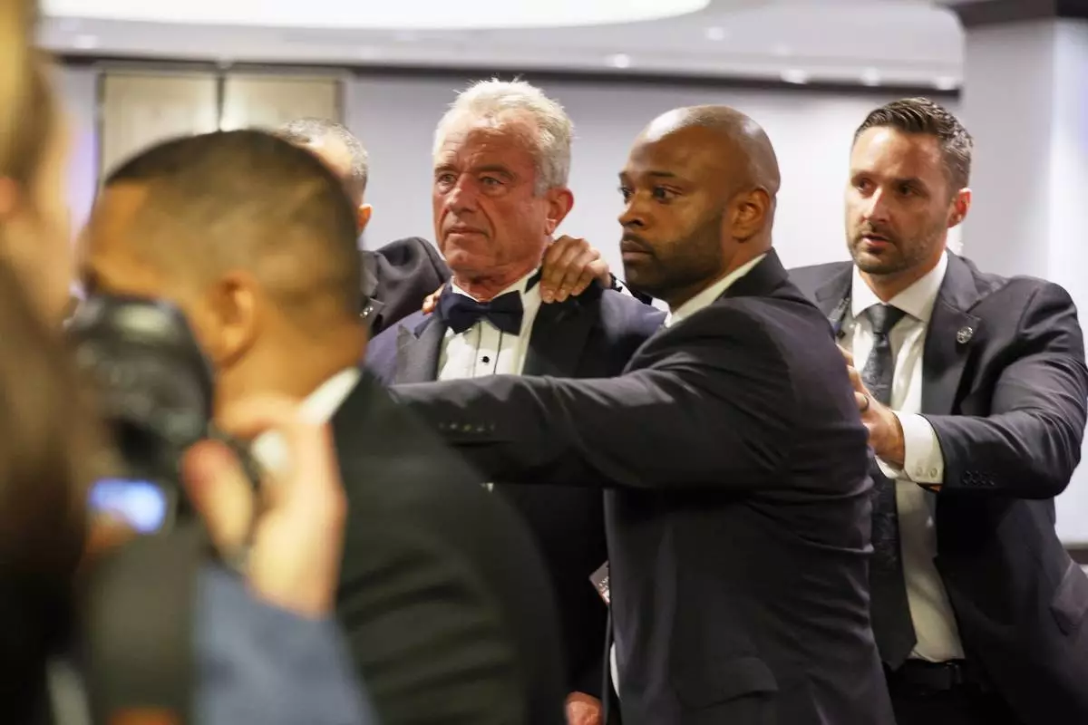 Security rapidly escort Secretary of Health and Human Services Robert F. Kennedy, Jr. out during the White House Correspondents Dinner, Saturday, April 25, 2026, in Washington. (AP Photo/Tom Brenner)