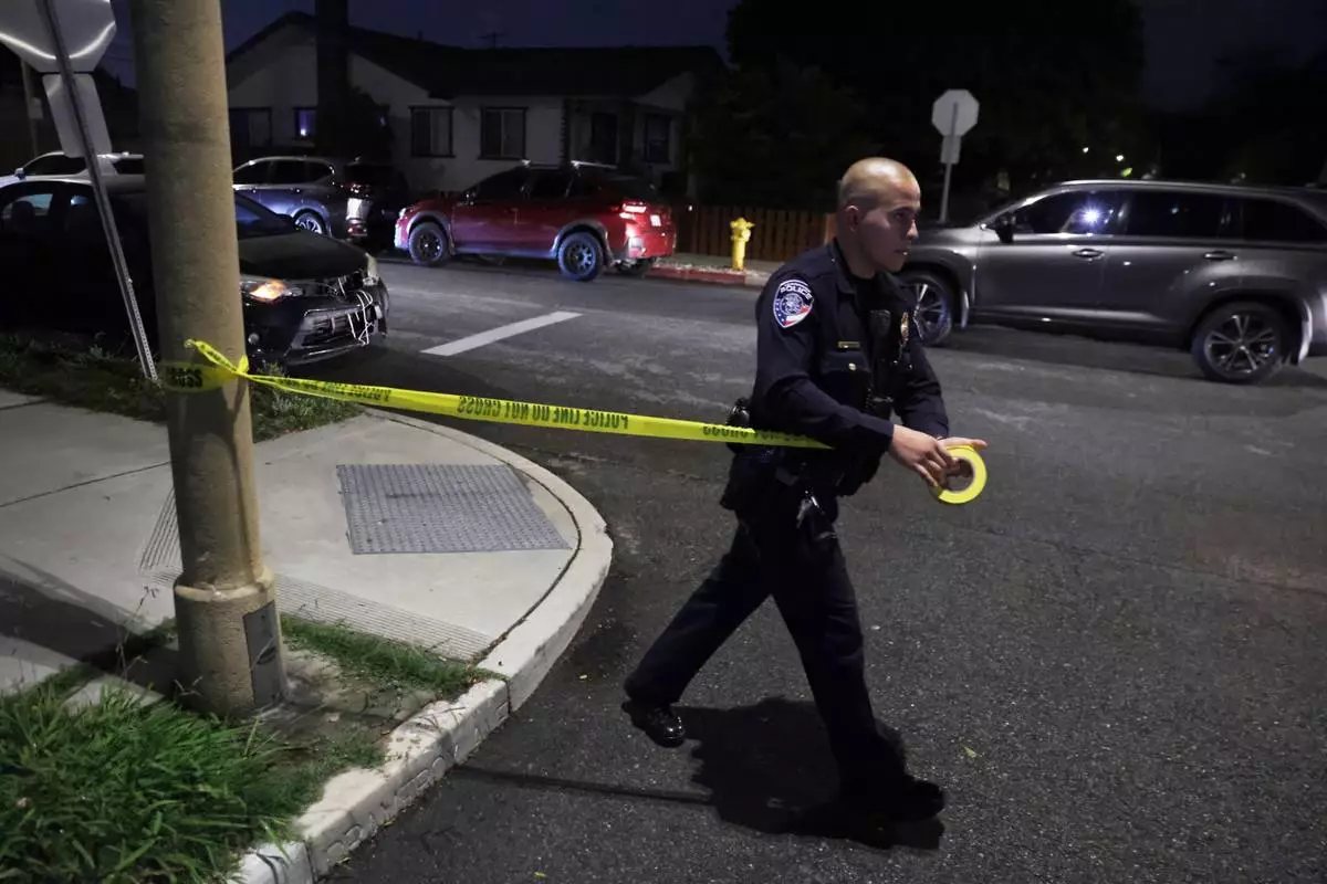 A law enforcement officer sets up police tape near an address connected to Cole Tomas Allen, the shooting suspect at the White House Correspondents Dinner on Saturday, April 25, 2026, in Torrance, Calif. (AP Photo/Ethan Swope)
