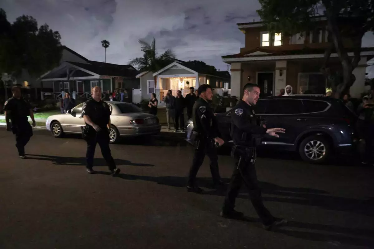 Law enforcement officials respond to an address connected to Cole Tomas Allen, the shooting suspect at the White House Correspondents Dinner, as people stand and watch on Saturday, April 25, 2026, in Torrance, Calif. (AP Photo/Ethan Swope)