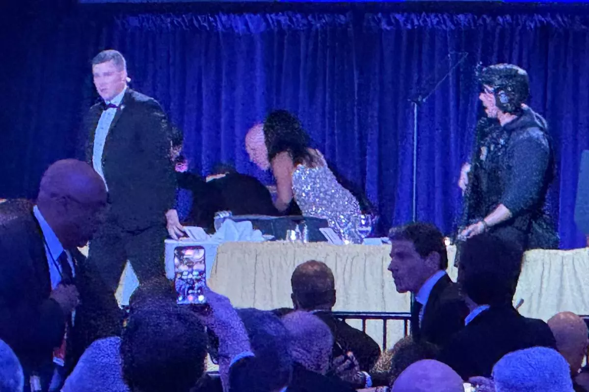U.S. Secret Service agents surround President Donald Trump as he is taken from the stage after a shooting incident outside the ballroom during the White House Correspondents Dinner, Saturday, April 25, 2026, in Washington. (AP Photo/Mark Schiefelbein)