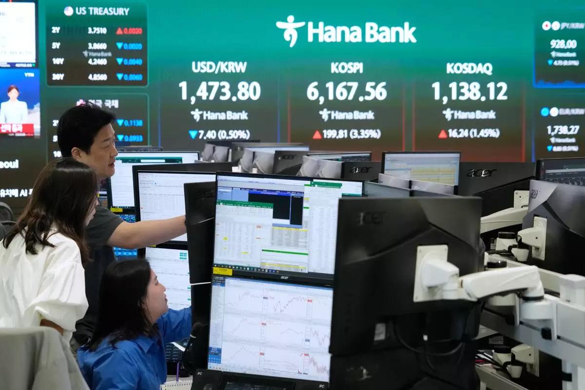 Currency traders watch monitors near a screen showing the Korea Composite Stock Price Index (KOSPI), top center, and the foreign exchange rate between U.S. dollar and South Korean won, top center left, at the foreign exchange dealing room of the Hana Bank headquarters in Seoul, South Korea, Wednesday, April 15, 2026. (AP Photo/Ahn Young-joon)