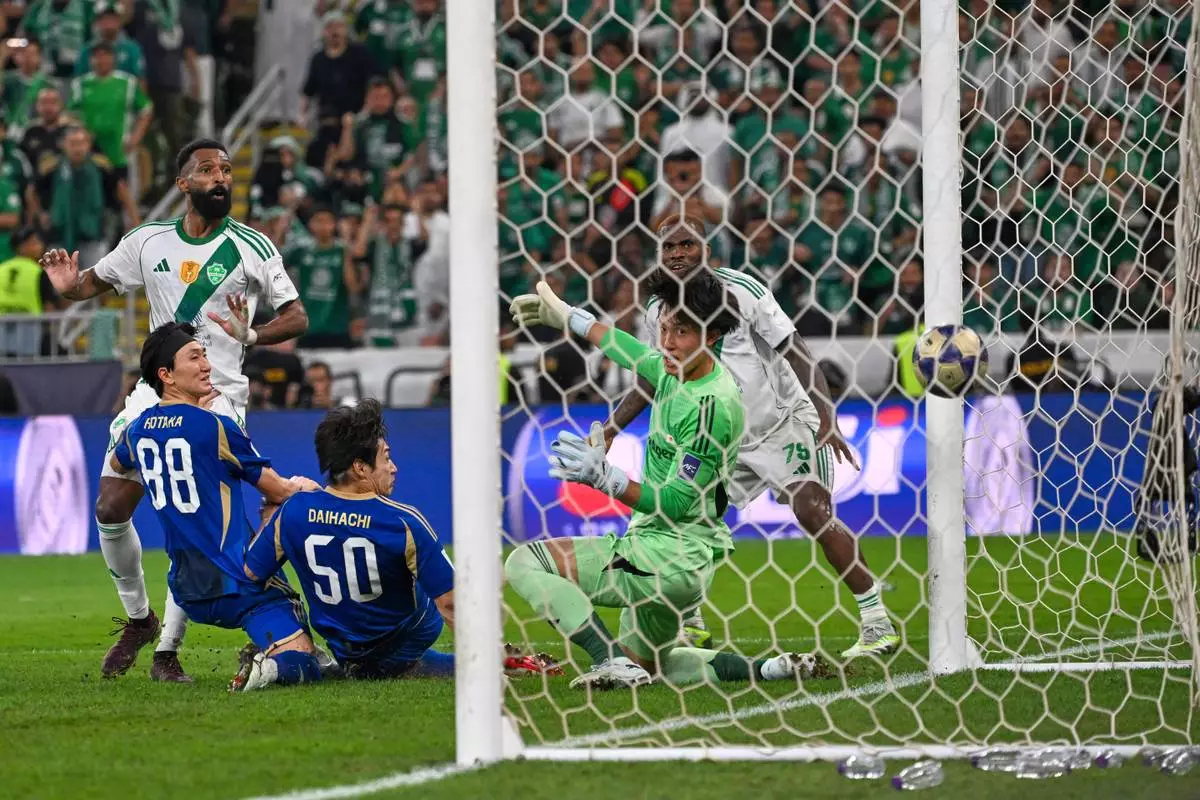 Al-Ahli's Feras Albrikan, left, scores at Machida Zelvia's goal keeper Kosei Tani, during the AFC Champions League Elite Final soccer match between Al-Ahli and Machida Zelvia at King Abdullah Sports City Stadium, in Jeddah, Saudi Arabia, Saturday, April 25, 2026. (AP Photo/Ali Issa)
