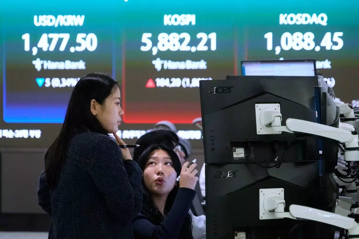 Currency traders work near a screen showing the Korea Composite Stock Price Index (KOSPI), top center, and the foreign exchange rate between U.S. dollar and South Korean won, top center left, at the foreign exchange dealing room of the Hana Bank headquarters, in Seoul, South Korea, Friday, April 10, 2026. (AP Photo/Ahn Young-joon)