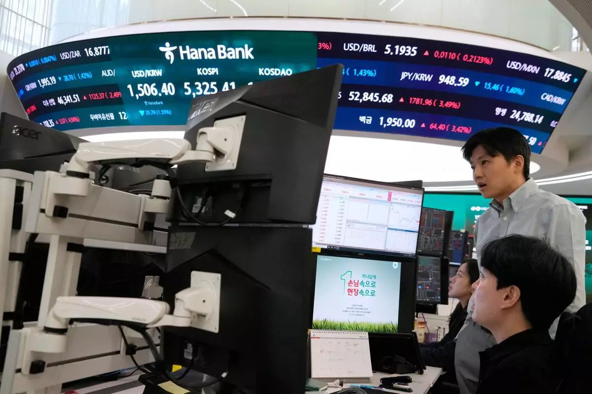 Currency traders watch monitors near a screen showing the Korea Composite Stock Price Index (KOSPI), top center, and the foreign exchange rate between U.S. dollar and South Korean won, top center left, at the foreign exchange dealing room of the Hana Bank headquarters in Seoul, South Korea, Wednesday, April 1, 2026. (AP Photo/Ahn Young-joon)