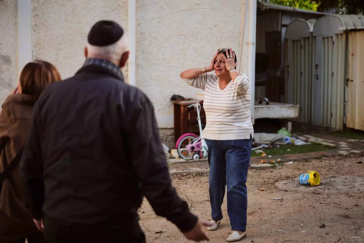 FILE - A woman reacts at the site of a damaged residential building after it was struck by a projectile fired from Lebanon, in Nahariya, northern Israel Monday, April 13, 2026. (AP Photo/Ariel Schalit, File)