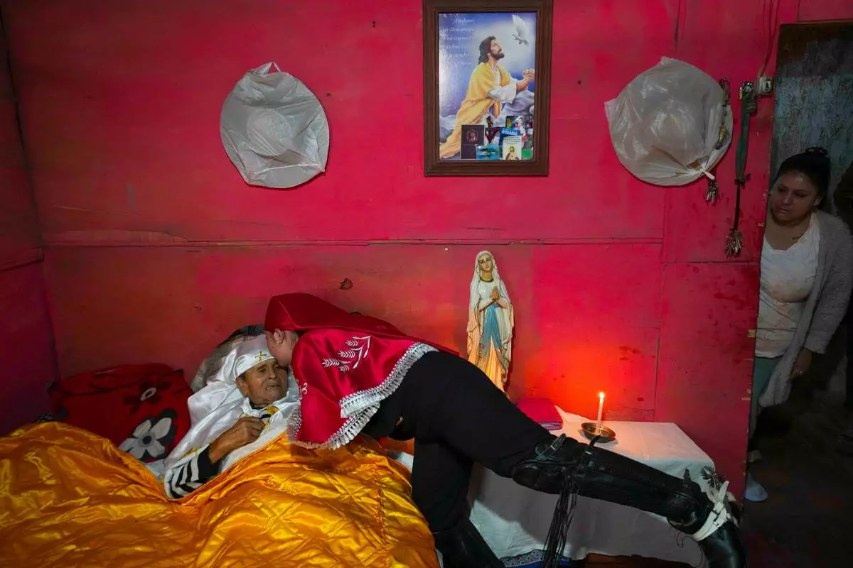 FILE - A pilgrim kisses her sick grandfather, Ramon Gamboa, after a priest blessed him at his home during the Quasimodo Feast, a procession held the Sunday following Easter, Colina, Chile, Sunday, April 12, 2026. (AP Photo/Esteban Felix, FIle)