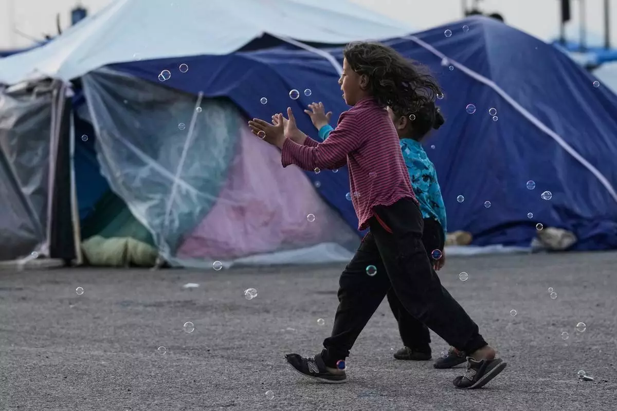 Girls chase bubbles next to their family's tents used as shelter after fleeing Israeli bombardment in Dahiyeh, Beirut's southern suburbs, in Beirut, on Wednesday, April 15, 2026. (AP Photo/Bilal Hussein)