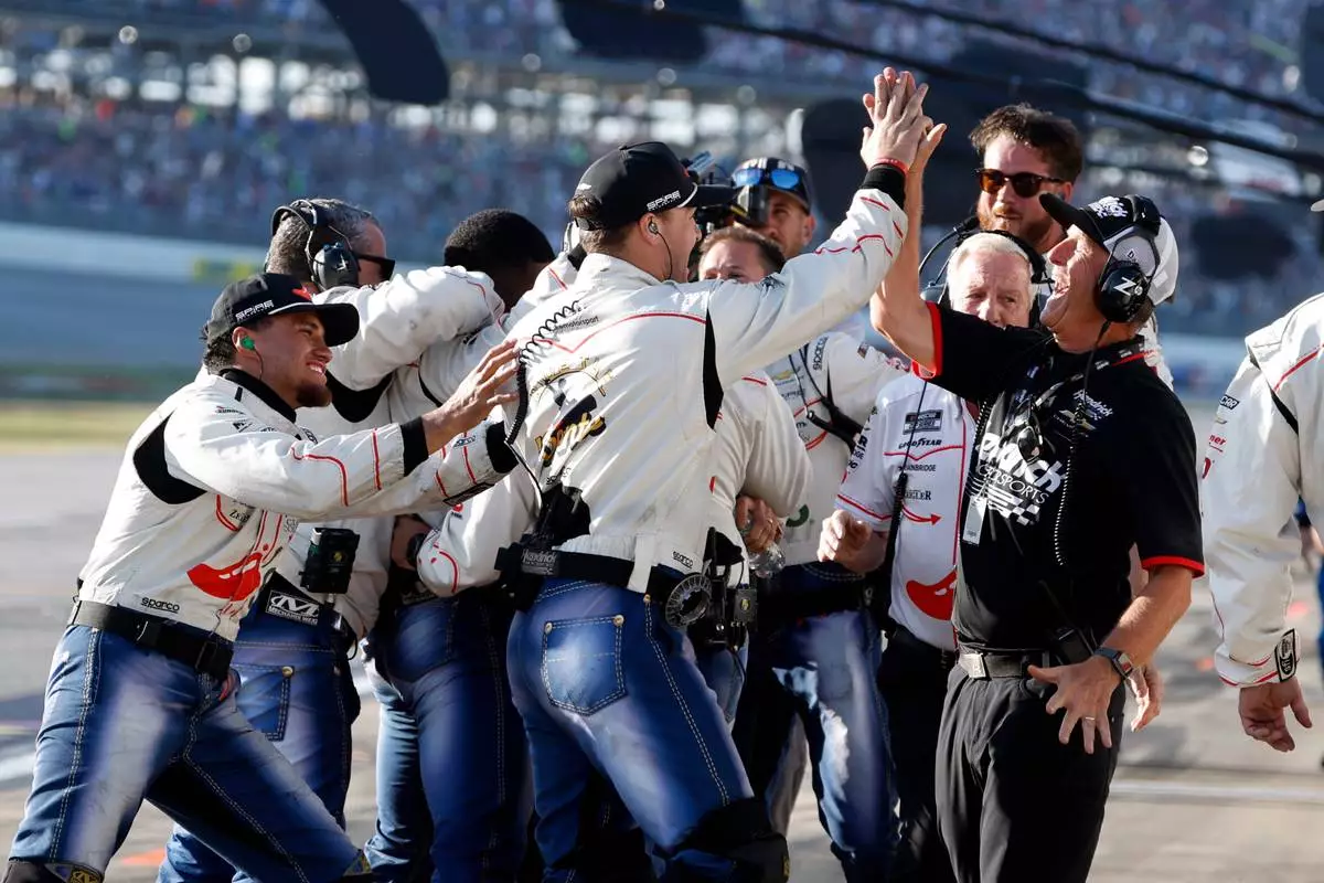 The crew of driver Carson Hocevar celebrate after his win in a NASCAR Cup Series auto race, Sunday, April 26, 2026, in Talladega, Ala. (AP Photo/Butch Dill)