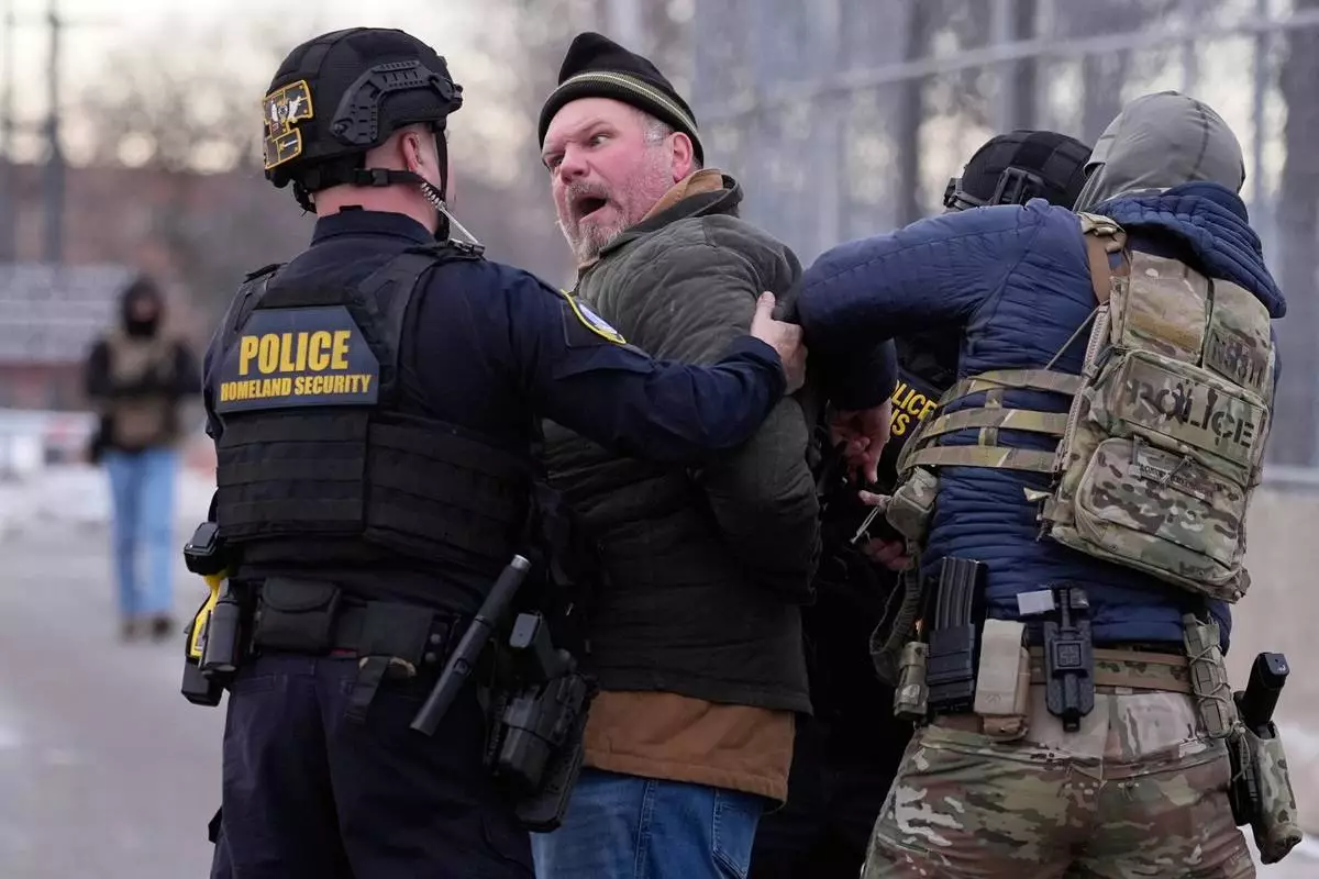 FILE - Law enforcement detain a man outside the Bishop Henry Whipple Federal Building during a protest, Jan. 17, 2026, in Minneapolis. (AP Photo/Yuki Iwamura, File)