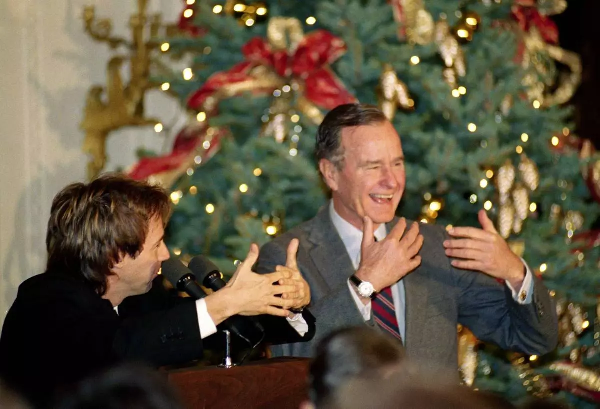FILE - Comic Dana Carvey, left, shows President George H.W. Bush how to imitate himself, Dec. 8, 1992, at the White House in Washington. (AP Photo/Dennis Cook, File)