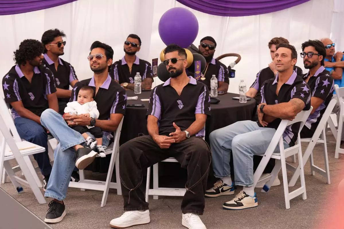 Unmurkt Chand holds his baby, Krishay, with members of the Los Angeles Knight Riders, cricket team form a LA sign with their hands as they pose for a picture at the Pomona Fairplex on Wednesday, April 22, 2026, during the groundbreaking ceremony of the new Knight Riders Cricket Field, which will serve as the Los Angeles Knight Riders' official home field for 2026 and later host cricket at the LA 2028 Olympics. (AP Photo/Damian Dovarganes)