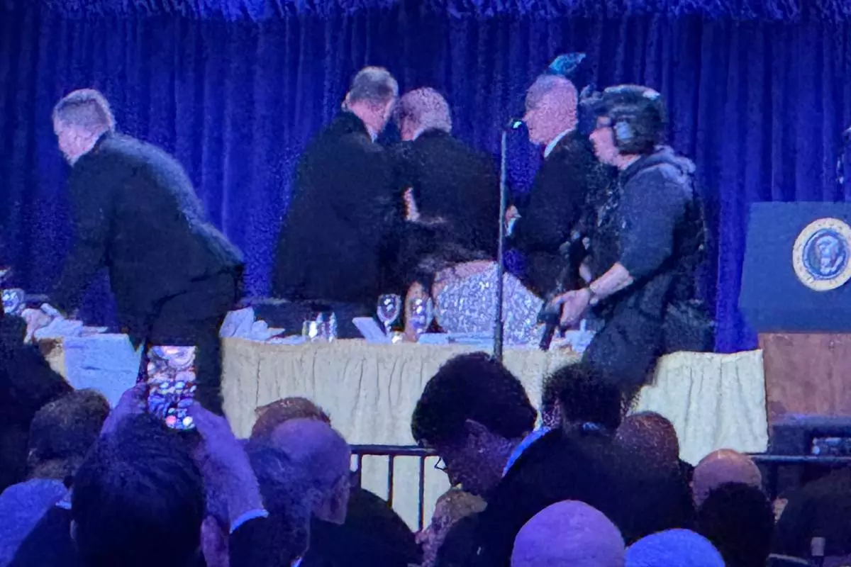 U.S. Secret Service agents surround President Donald Trump, third from left, as he is taken from the stage after a shooting incident outside the ballroom during the White House Correspondents Dinner, Saturday, April 25, 2026, in Washington. (AP Photo/Mark Schiefelbein)