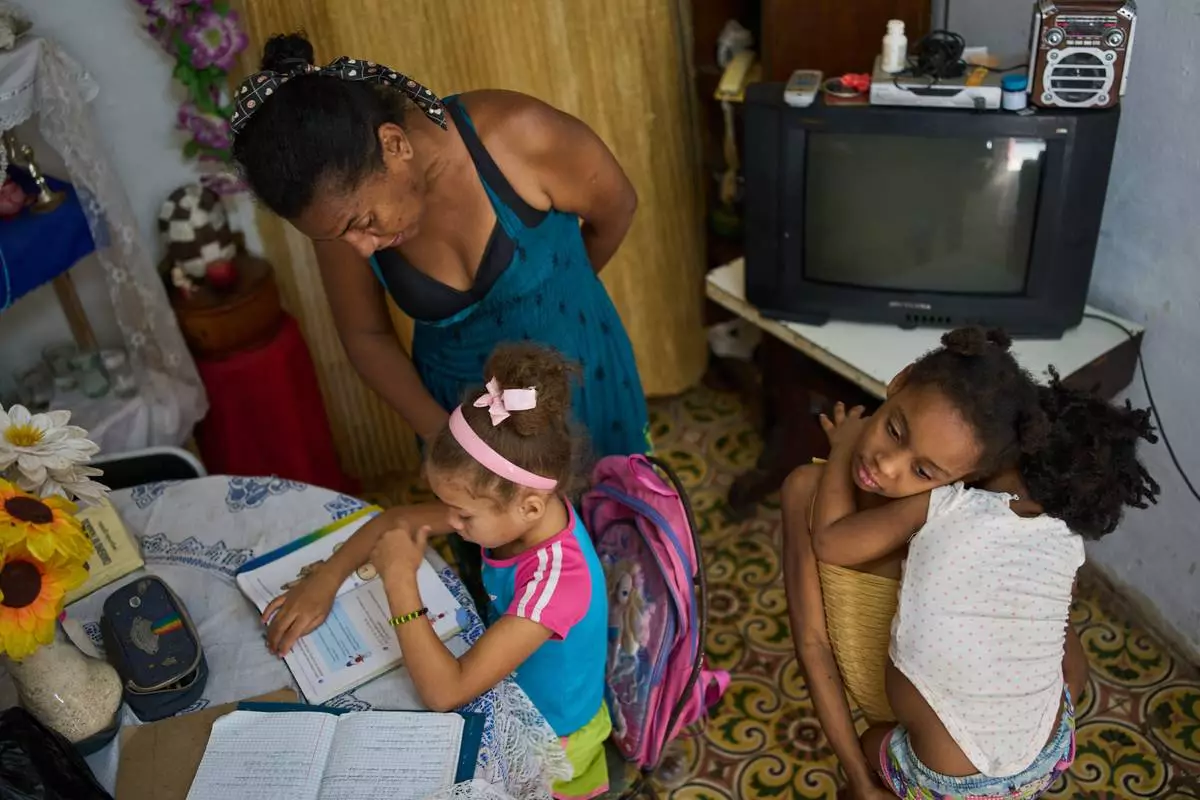 FILE - Yuneisy Riviaux helps her daughter Edianet with her homework at their home in Havana, Cuba, March 25, 2026. (AP Photo/Ramon Espinosa, File)