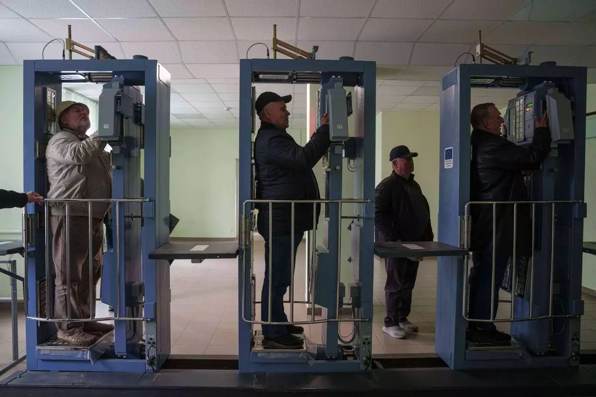 Workers who were sent to clean up contamination from the 1986 Chernobyl nuclear power plant accident, pass through a radiation inspection point, Tuesday, April 21, 2026, at the plant in Chernobyl, Ukraine. (AP Photo/Evgeniy Maloletka)