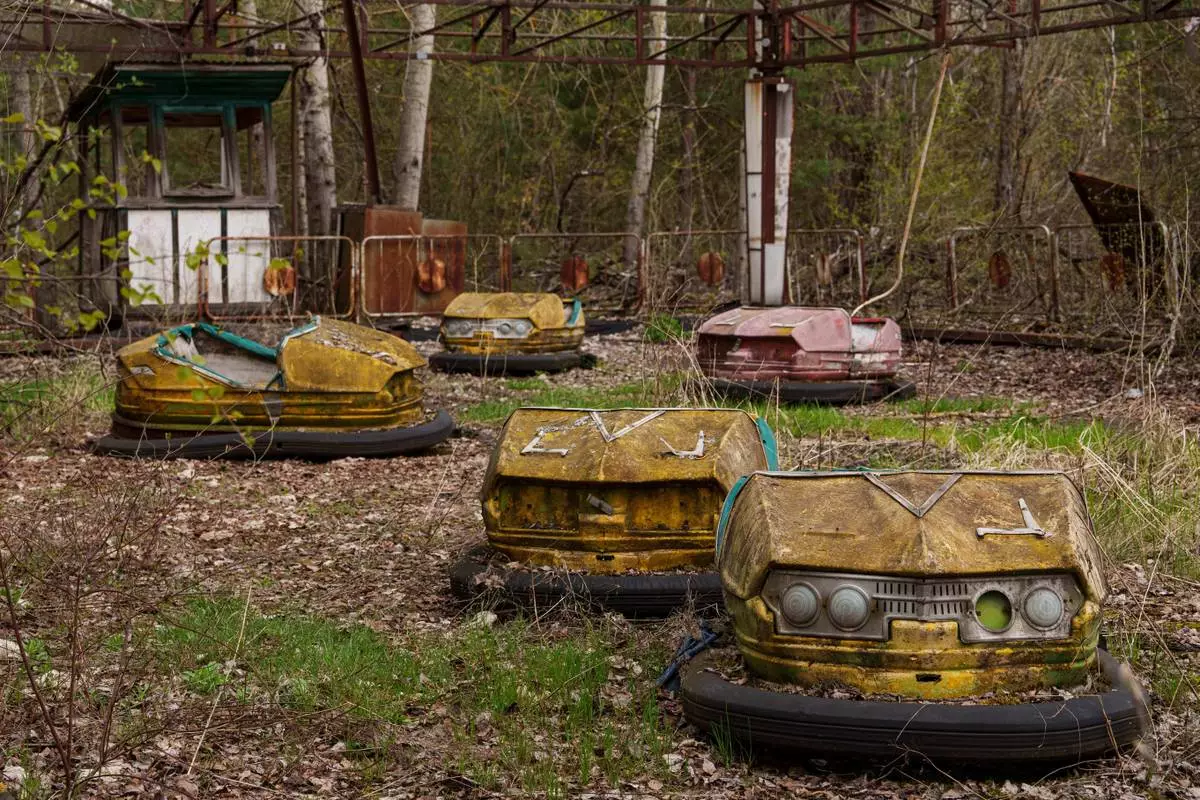 Bumper cars sit idle at an overgrown amusement park in Pripyat, Ukraine, a town left abandoned following the nearby 1986 Chernobyl nuclear disaster, Tuesday, April 21, 2026. (AP Photo/Evgeniy Maloletka)