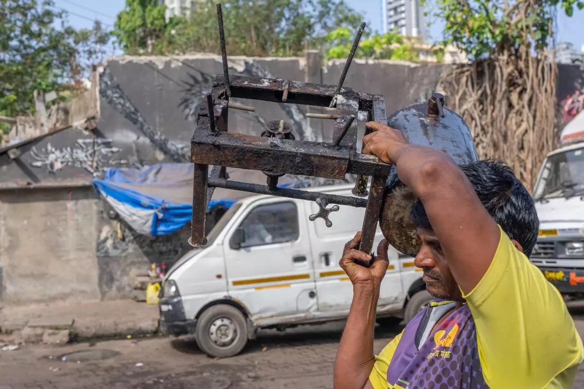 A fisherman carries a stove as he walks towards his boat at Sassoon Dock In Mumbai, India, Wednesday, April 8, 2026. (AP Photo/Rafiq Maqbool)