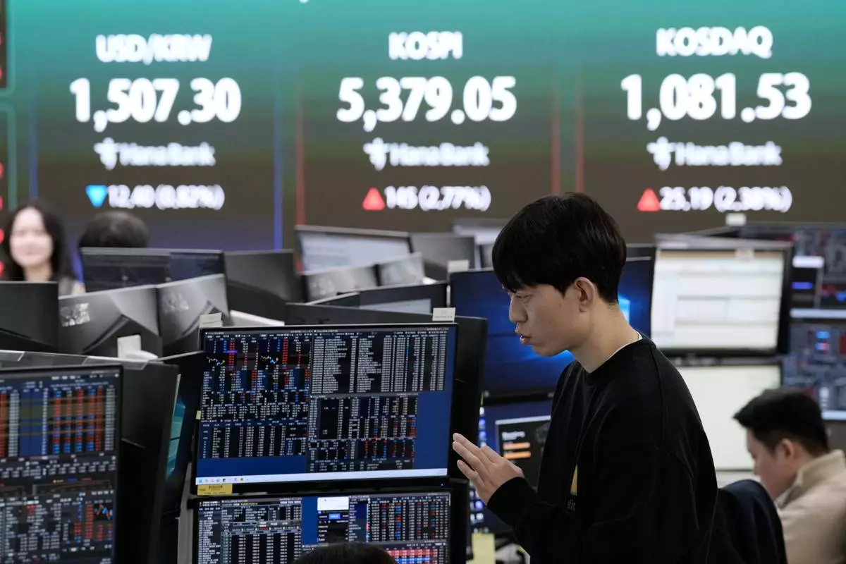A currency trader works near a screen showing the Korea Composite Stock Price Index (KOSPI), top center, and the foreign exchange rate between U.S. dollar and South Korean won, top center left, at the foreign exchange dealing room of the Hana Bank headquarters in Seoul, South Korea, Friday, April 3, 2026. (AP Photo/Ahn Young-joon)