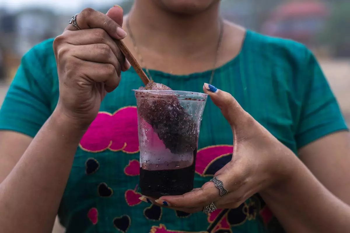 FILE - A girl hold a plastic glass as she prepares to drink Shaved ice at Juhu beach in Mumbai, India, on June 30, 2022. (AP Photo/Rafiq Maqbool, File)