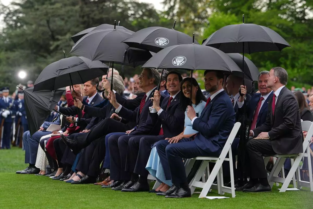 Members of the United States and British delegations use umbrellas at an arrival ceremony on the South Lawn of the White House, Tuesday, April 28, 2026, in Washington. (AP Photo/Julia Demaree Nikhinson)
