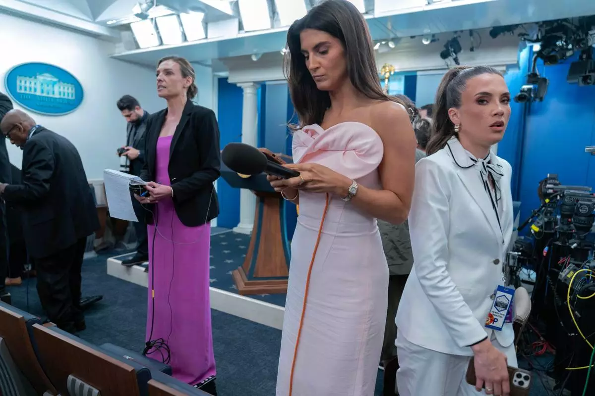 Reporters dressed in evening gowns gala wait for President Donal Trump to speak in the James Brady Press Briefing Room at the White House after a shooting incident outside the ballroom at at the annual White House Correspondents' Association dinner in Washington, Saturday, April 25, 2026. (AP Photo/Jose Luis Magana)