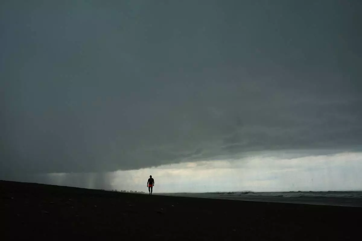 A man walks on the beach as a rain storm moves in to Mar de las Pampas, Argentina, Friday, April 3, 2026. (AP Photo/Rodrigo Abd)
