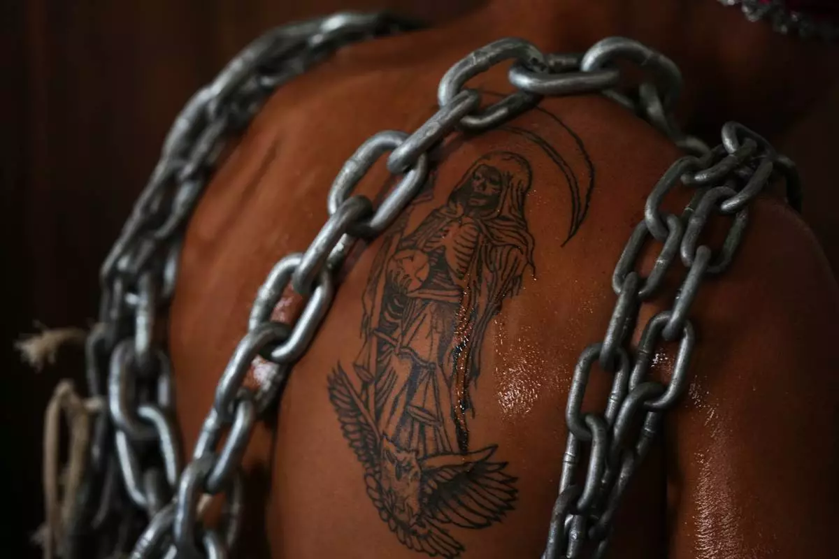 Chains drape over the Santa Muerte tattoo of a penitent before a Good Friday procession during Holy Week in Atlixco, Mexico, Friday, April 3, 2026. (AP Photo/Fernando Llano)