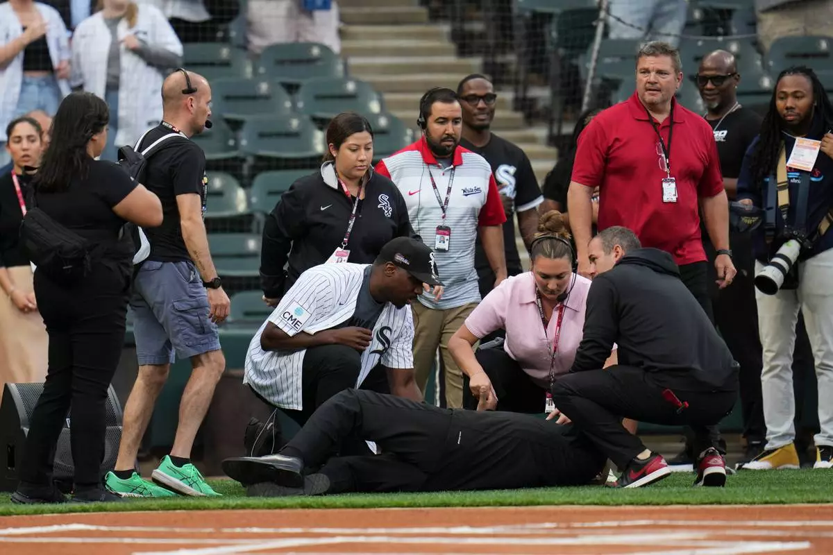 People tend to a man who collapsed while singing "Lift Every Voice and Sing" before a baseball game between the Tampa Bay Rays and Chicago White Sox, Wednesday, April 15, 2026, in Chicago. (AP Photo/Erin Hooley) CORRECTION: Corrects from Life to Lift