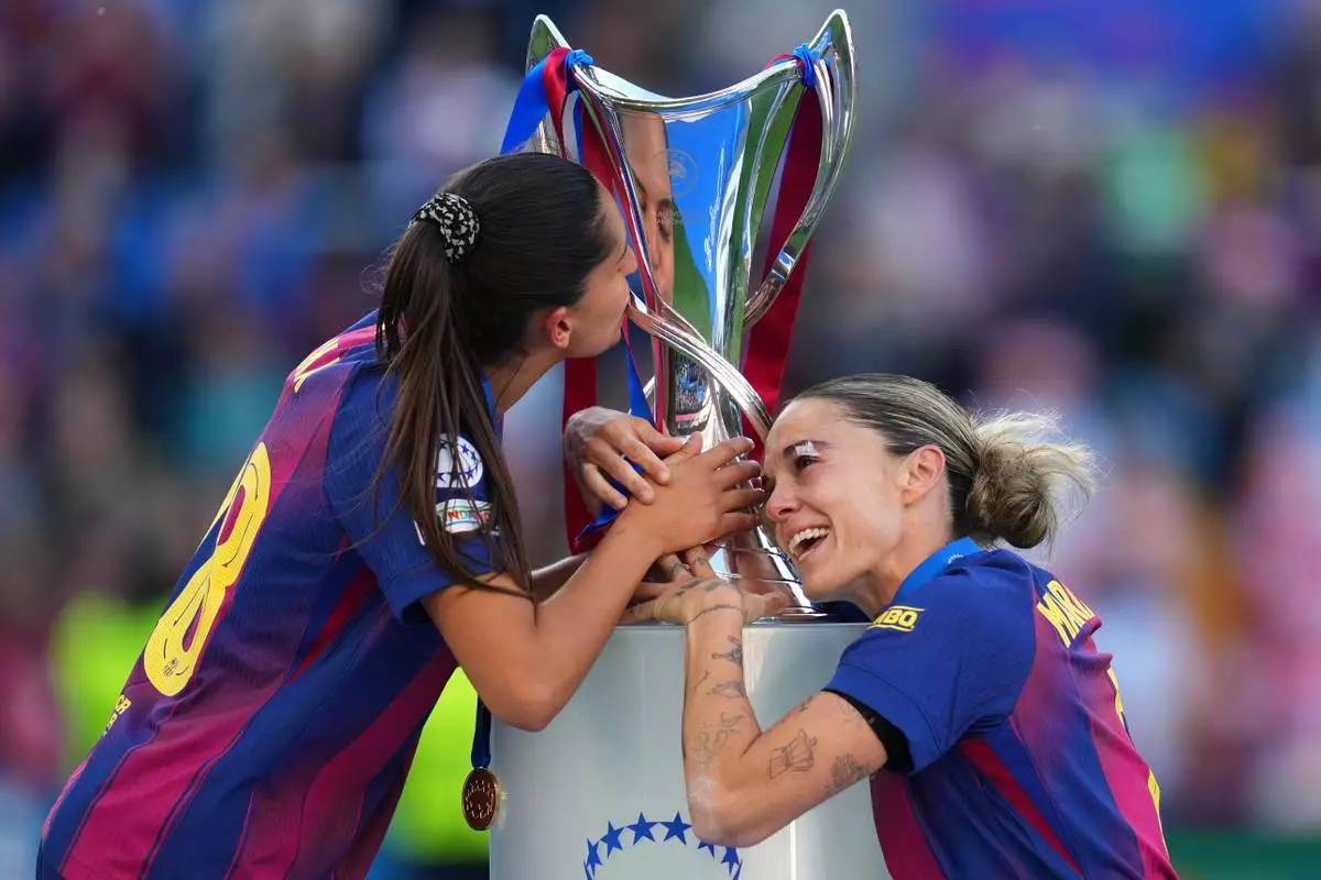 Barcelona's Kika Nazareth, left, and Mapi Leon touch the trophy after winning the Women's Champions League final soccer match between FC Barcelona and OL Lyonnes, in Oslo, Saturday, May 23, 2026. (AP Photo/Kirsty Wigglesworth)