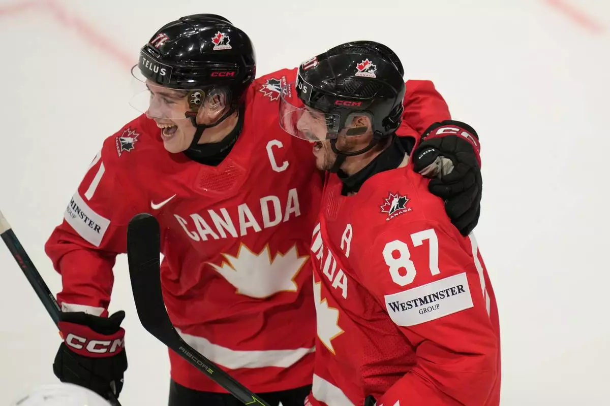 Canada's Sidney Crosby (87) celebrates with Macklin Celebrini (71) after scoring a goal during the third period of the 2026 IIHF Men's Ice Hockey World Championship quarterfinal match between Canada and United States, in Fribourg, Switzerland, Thursday, May 28, 2026. (AP Photo/Darko Bandic)