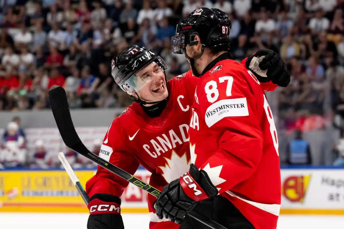 Canada's Sidney Crosby (87) celebrates with Macklin Celebrini (71) after scoring a goal during the third period of the 2026 IIHF Men's Ice Hockey World Championship quarterfinal match between Canada and United States, in Fribourg, Switzerland, Thursday, May 28, 2026. (Anthony Anex/Keystone via AP)
