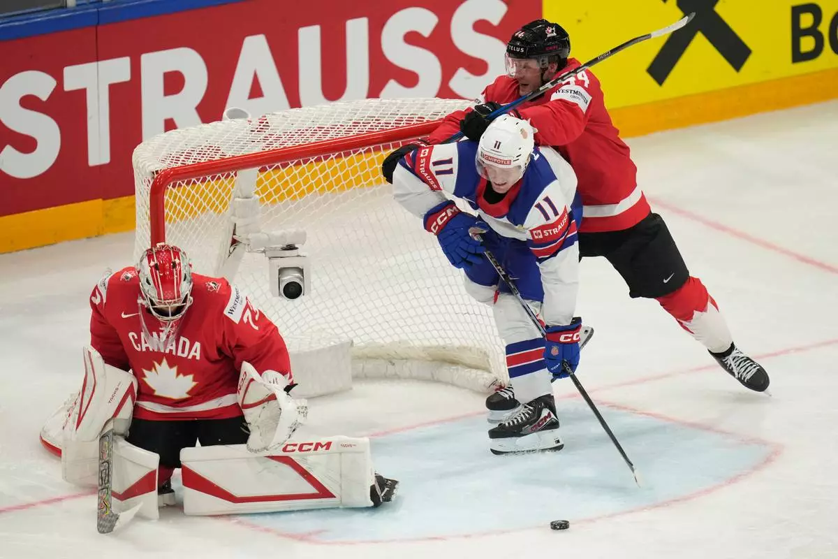 Canada goalkeeper Jet Greaves (73) and Morgan Rielly (44) defend against pressure from United States' Oliver Moore (11) during the third period of the 2026 IIHF Men's Ice Hockey World Championship quarterfinal match between Canada and United States, in Fribourg, Switzerland, Thursday, May 28, 2026. (AP Photo/Darko Bandic)