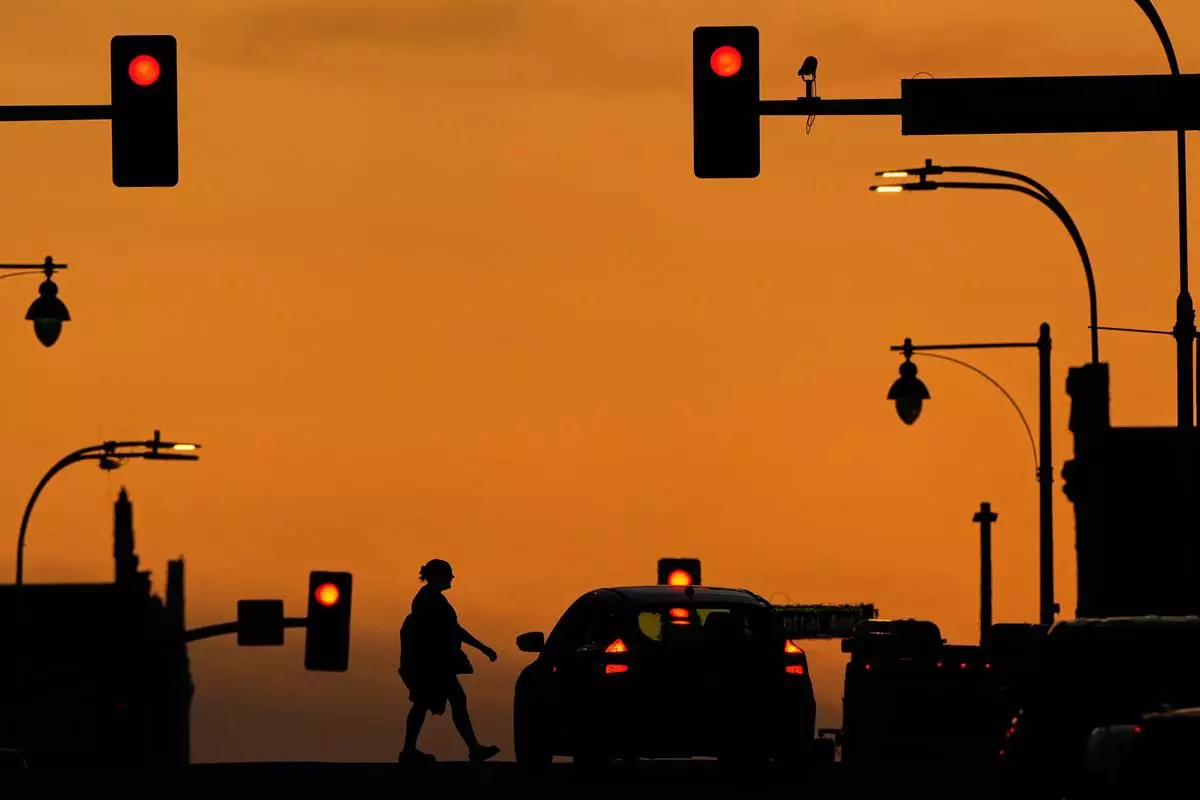 FILE - A person crosses a downtown street as the sun sets, March 31, 2025, in Kansas City, Mo. (AP Photo/Charlie Riedel, file)