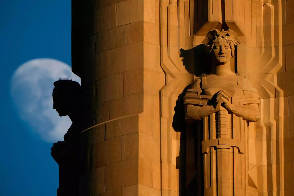 FILE - The moon rises beyond sculptures atop the Liberty Memorial tower at the National World War I Museum, July 6, 2025, in Kansas City, Mo. (AP Photo/Charlie Riedel, file)