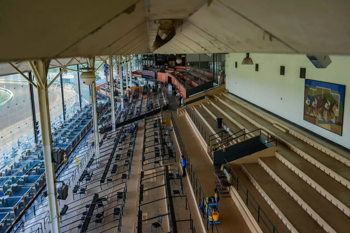 The Laurel Park grandstand sits almost empty as a janitor mops the floor during live racing, Friday, May 8, 2026, in Laurel, Md. (AP Photo/Julia Demaree Nikhinson)