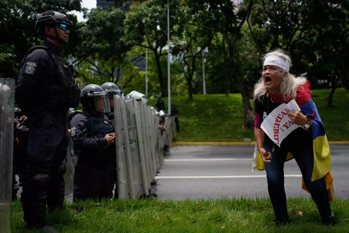 FILE - An activist screams "freedom" at Bolivarian National Police standing guard during a University student protest on a main highway in Caracas, Venezuela, May 13, 2026. (AP Photo/Ariana Cubillos, File)