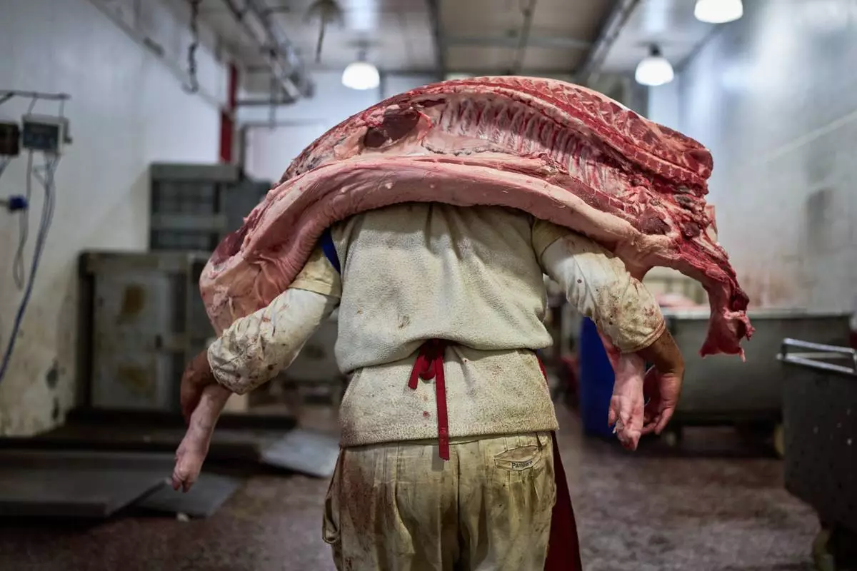 FILE - A worker carries pork inside a butcher shop at the Mataderos meat market in Buenos Aires, Argentina, May 14, 2026. (AP Photo/Rodrigo Abd, File)