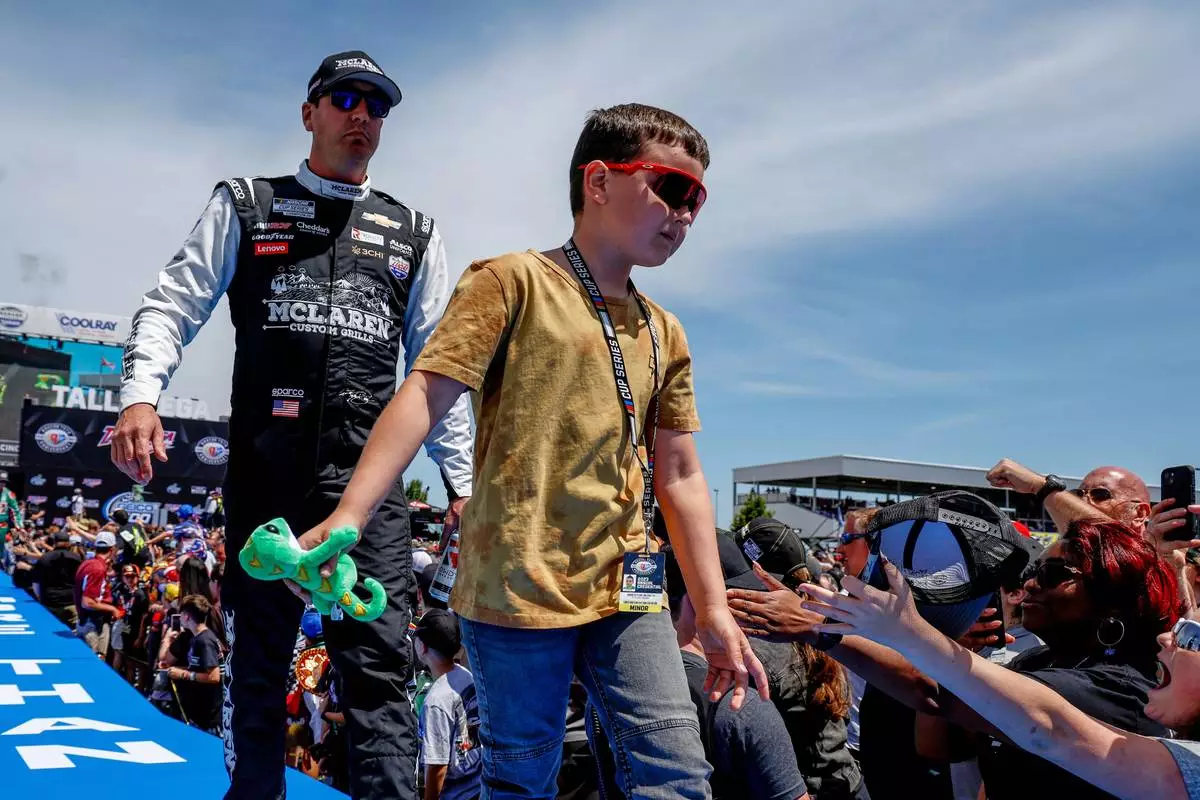 FILE - Kyle Busch, left, and his son greet fans before a NASCAR Cup Series auto race at Talladega Superspeedway, April 23, 2023, in Talladega, Ala. (AP Photo/Butch Dill, File)