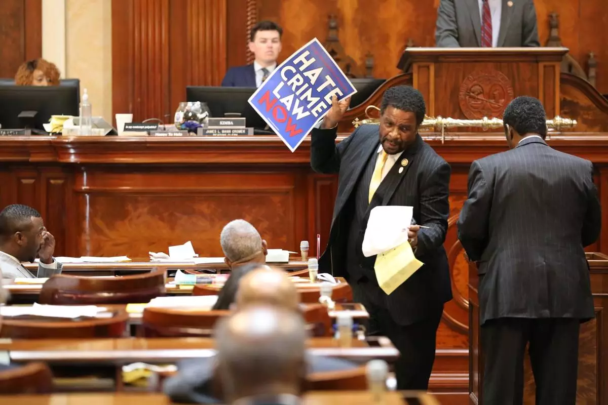 Democratic South Carolina Rep. Wendell Gillard walks back to his desk with a sign after giving a speech during the redistricting debate on Tuesday. May 19, 2026, in Columbia, S.C. (AP Photo/Jeffrey Collins)