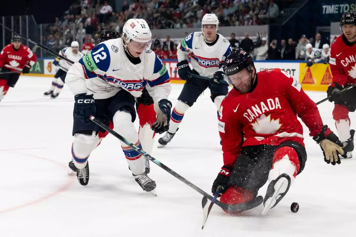 Norway's Noah Steen, left, and Canada's Morgan Rielly fight for the puck during the 2026 IIHF Men's Ice Hockey World Championship preliminary round group B game between Canada and Norway, in Fribourg, Switzerland, Thursday, May 21, 2026. (Anthony Anex/Keystone via AP)