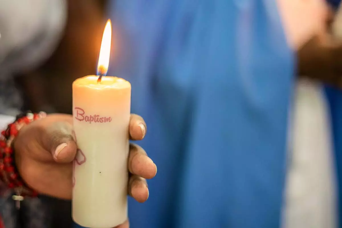 A parent holds a candle during a baptism ceremony at the Roman Catholic Cathedral in Harare, Zimbabwe, Sunday, April 5, 2026. (AP Photo/Aaron Ufumeli)