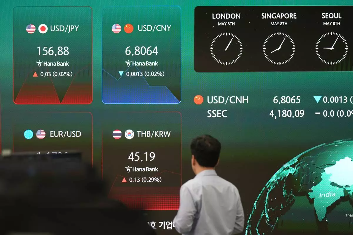 A dealer walks past near the screens showing the foreign exchange rates at a dealing room of Hana Bank in Seoul, South Korea, Friday, May 8, 2026. (AP Photo/Lee Jin-man)