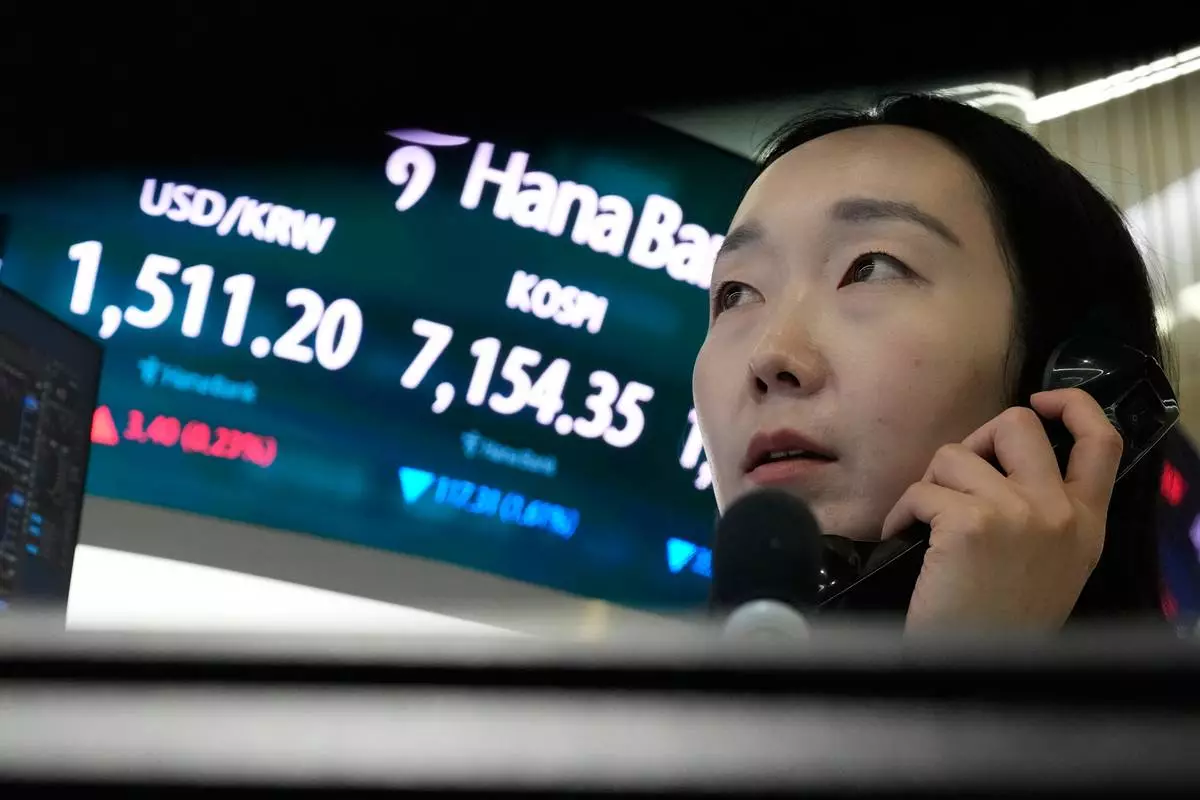A currency trader talks on the phone near a screen showing the Korea Composite Stock Price Index (KOSPI) and the foreign exchange rate between U.S. dollar and South Korean won, left, at the foreign exchange dealing room of the Hana Bank headquarters in Seoul, South Korea, Wednesday, May 20, 2026. (AP Photo/Ahn Young-joon)